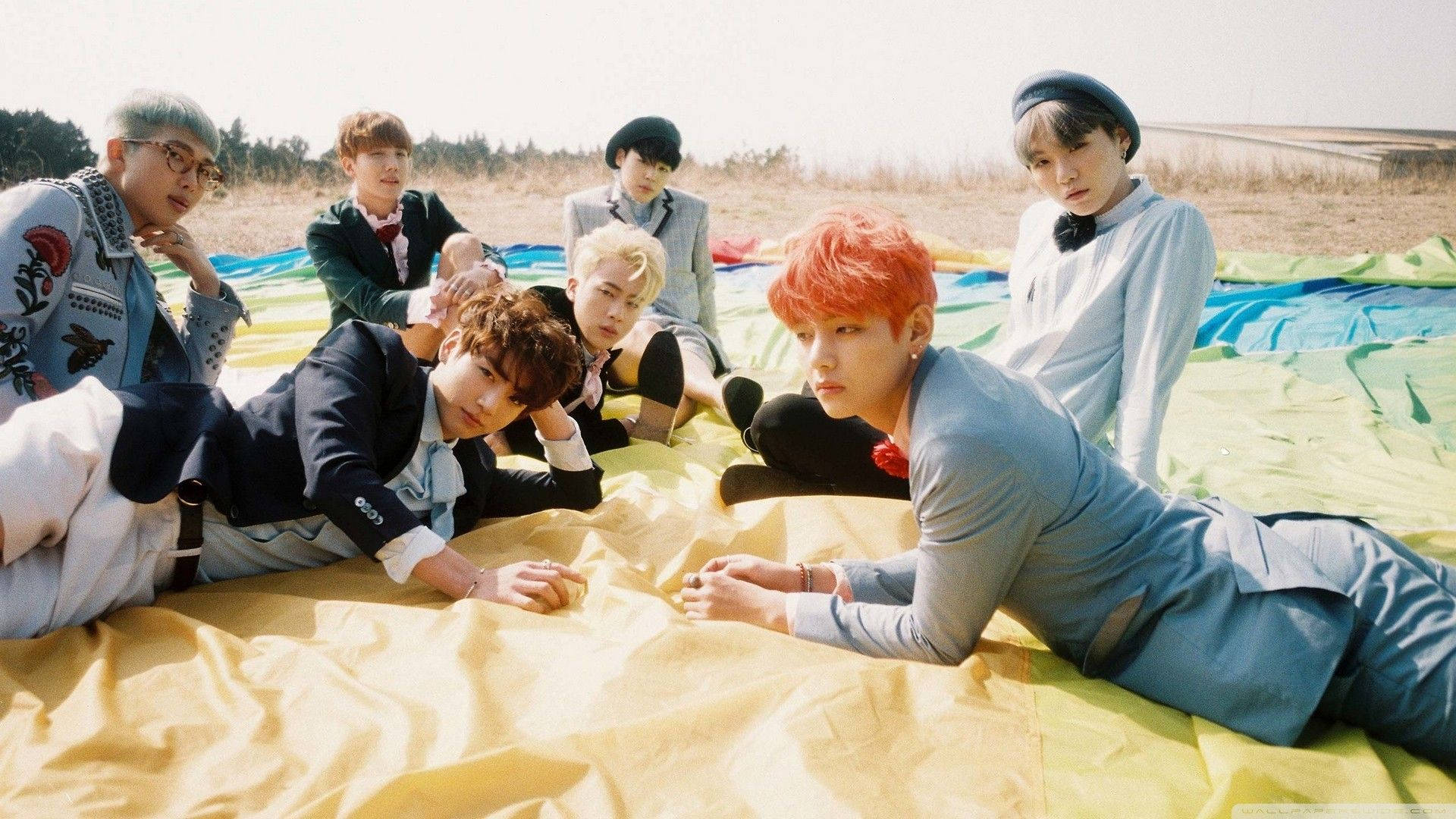 들판에서 노트북을 두고 누워 있는 BTS 멤버들 배경화면