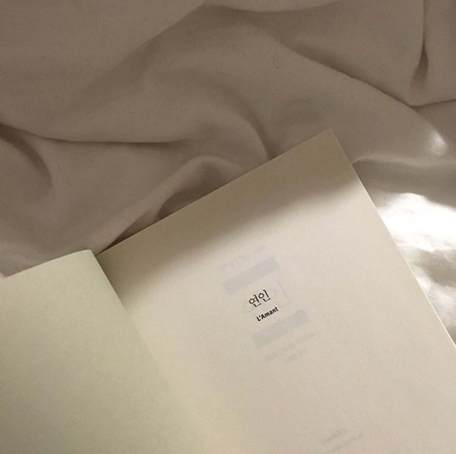 침대 위에 놓인 흰색 표지의 책 배경화면
