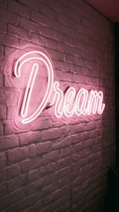 흰색 벽돌 벽에 빛나는 연분홍색 'Dream' 네온사인, 영감을 주고 감성적인. — 연핑크 감성 배경화면