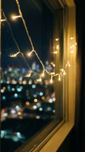 밤에 도시의 보케와 함께 창가에 놓인 요정 불빛. — 감성적인 크리스마스 배경화면