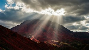 붉은 산 위로 구름을 뚫고 내리쬐는 햇살이 극적인 조명을 만들어내는 풍경